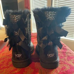 Childrens black and silver UGG boots with bows.
